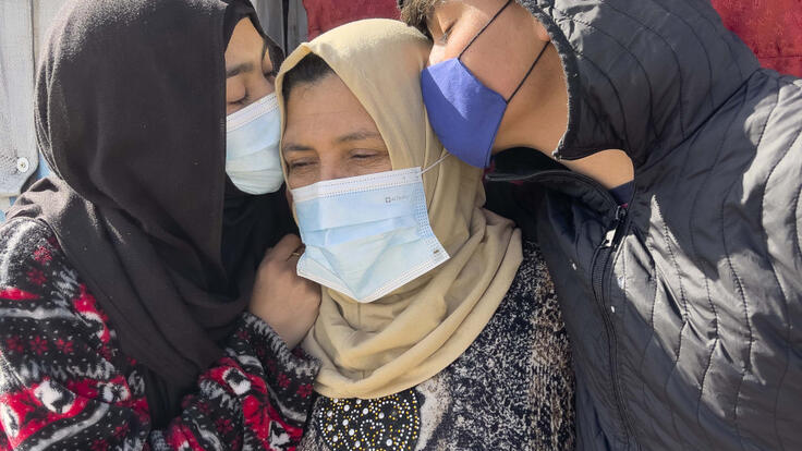 Lina standing to the left of her mother, with her brother Ahmad at the right. Both are kissing their mom on the head